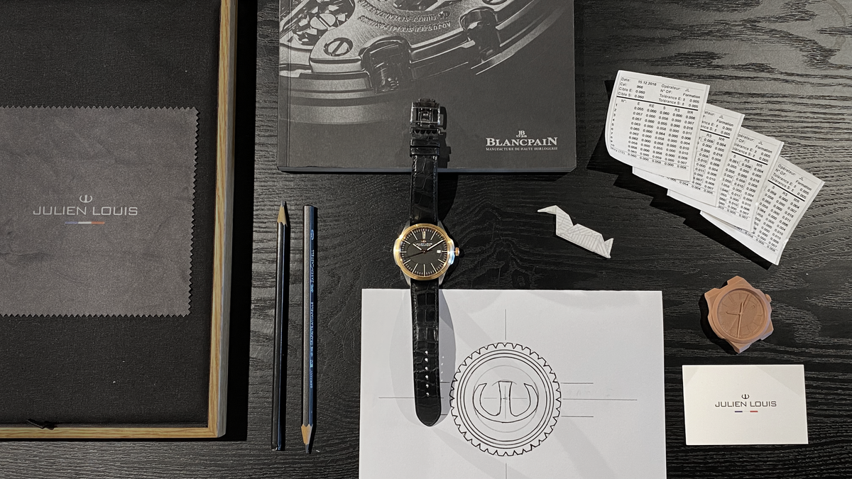 Montre Julien Louis posée sur un bureau avec des éléments retraçant l'histoire de la marque